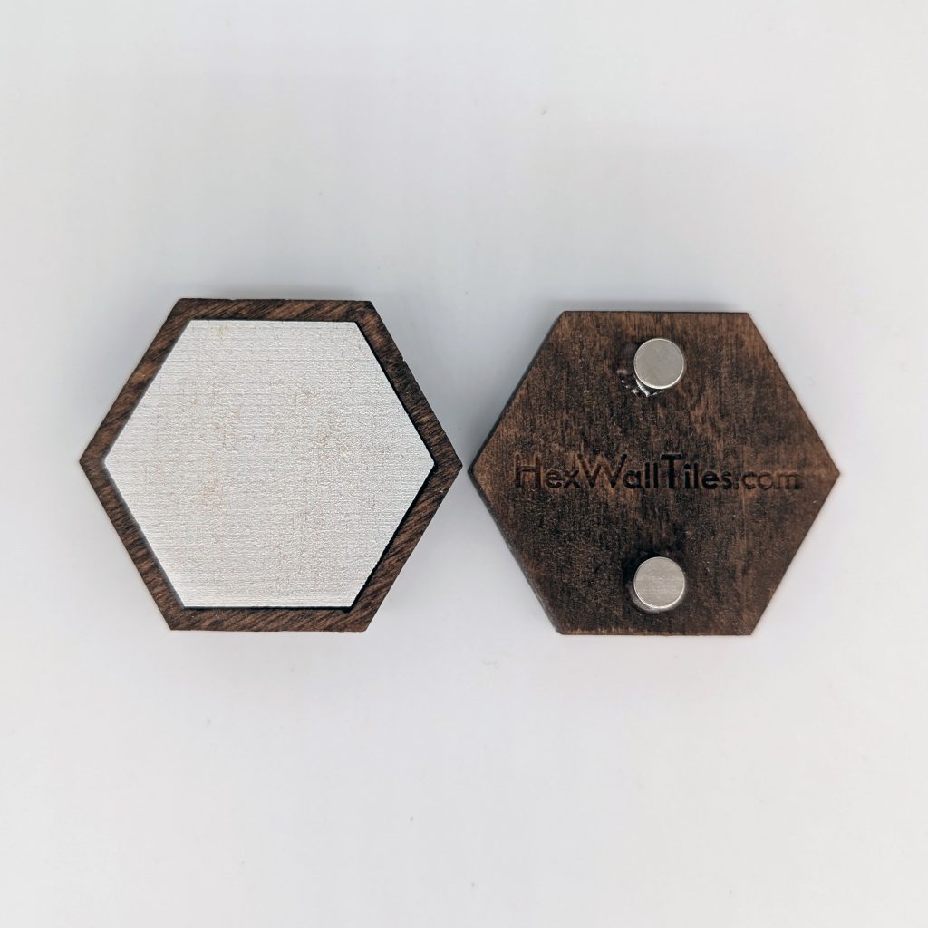 Two hexagon wood magnets in English Chestnut stain, left magnet shown with a blank white hex tile insert as a placeholder, right magnet shown from the back with two embedded round magnets and HexWallTiles.com engraving